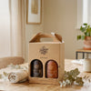 Two bottles in a cardboard gift box on a table with a neutral background